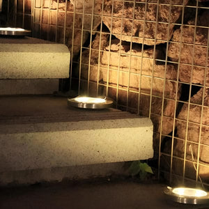 Vier Solarbodenleuchten mit silbernem Rand und schwarzer Spitze in einem Anwendungsbeispiel in einer Treppe