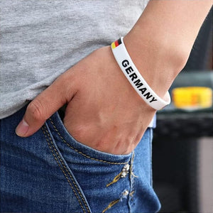 Weisses Silikonarmband mit schwarzer "Germany" Aufschrift und Deutschlandflagge an einem Arm