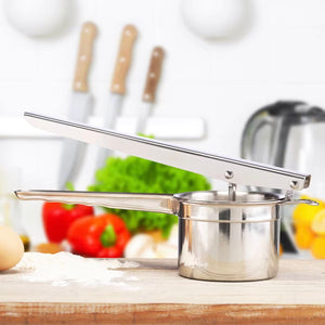 Silberne Kartoffelpresse mit Küche im Hintergrund