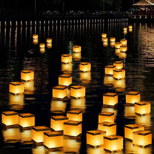 Weiss-goldene Laternen mit brennenden Kerzen in einem Anwendungsbeispiel auf einem See