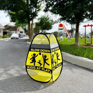Gelbes Strassenschild mit Abbildung von spielenden Kindern und "Slow down, kids at play" Aufschrift in einem Aufstellbeispiel auf einer Strasse