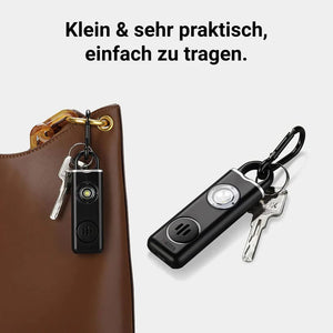 Schwarzer Personenalarm mit Lautsprecher und schwarzem Karabiner in einem Anwendungsbeispiel an einer Tasche