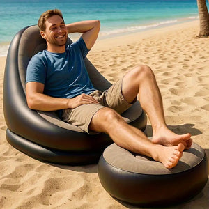 Aufgeblasener, beige-schwarzer Sessel mit kleinem aufgeblasenem Fusshocker in einem Anwendungsbeispiel mit einem Mann am Strand