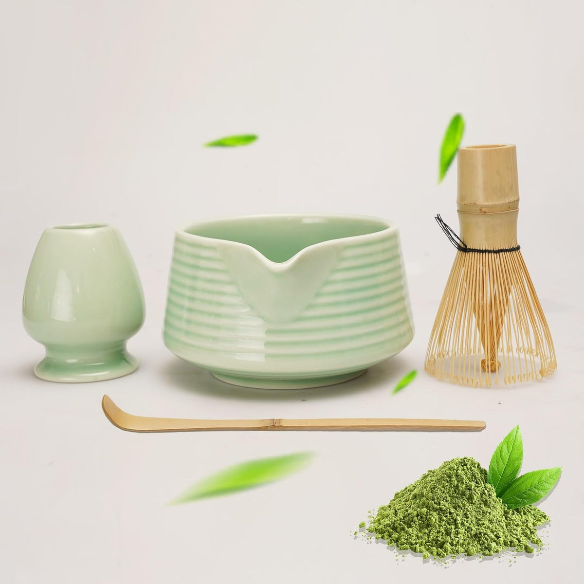 Matcha-Set mit Schale, Bambusbesen, Löffel und grünem Pulver auf hellem Hintergrund