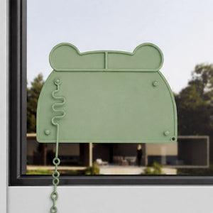 Grüne Silikonmatte in Bärenkopf-Form an einem Fenster befestigt