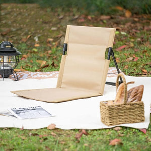 Verstellbare, beige Strandmatte mit schwarzer Stütze in einem Beispiel auf einer Wiese