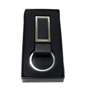 Schwarzer Schlüsselanhänger aus Leder mit silbernem Metallring und rechteckigem Metallrahmen an der Vorderseite in schwarzer Verpackung