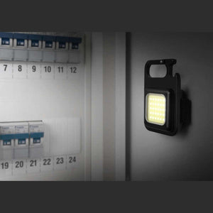 Kleines, quadratisches LED-Licht mit Ständer und Karabiner an einer Wand befestigt