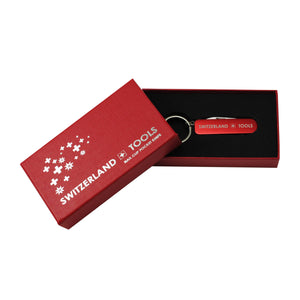 Roter Nagelclipper und Schlüsselanhänger mit "Switzerland-Tools" Aufschrift in roter Kartonverpackung mit schwarzem Kunststoff und silbernem Design