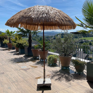 Beiger Sonnenschirm mit Holz Ständer im Hawaii Stil in einem Anwendungsbeispiel auf einer Terrasse