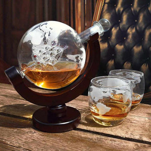 Flasche in Form eines Globus mit zwei Gläsern daneben auf einem Holztisch