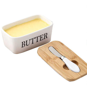 Weisser Butterbehälter mit schwarzer "Butter" Aufschrift neben Holzdeckel, Buttermesser