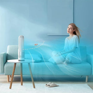 Grauer Turmventilator in Form eines Ovals auf einem kleinen Tisch und einem Sofa mit Person im Hintergrund