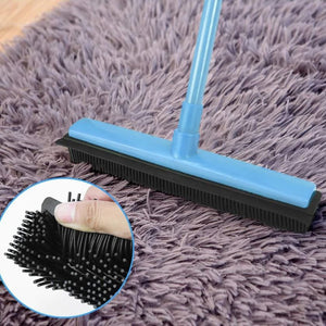 Blauer Besen mit schwarzen Gummiborsten in einem Anwendungsbeispiel auf einem Teppich