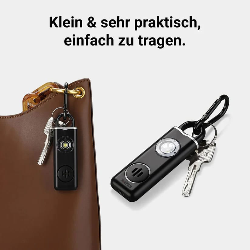 Schwarzer Personenalarm mit Lautsprecher und schwarzem Karabiner in einem Anwendungsbeispiel an einer Tasche