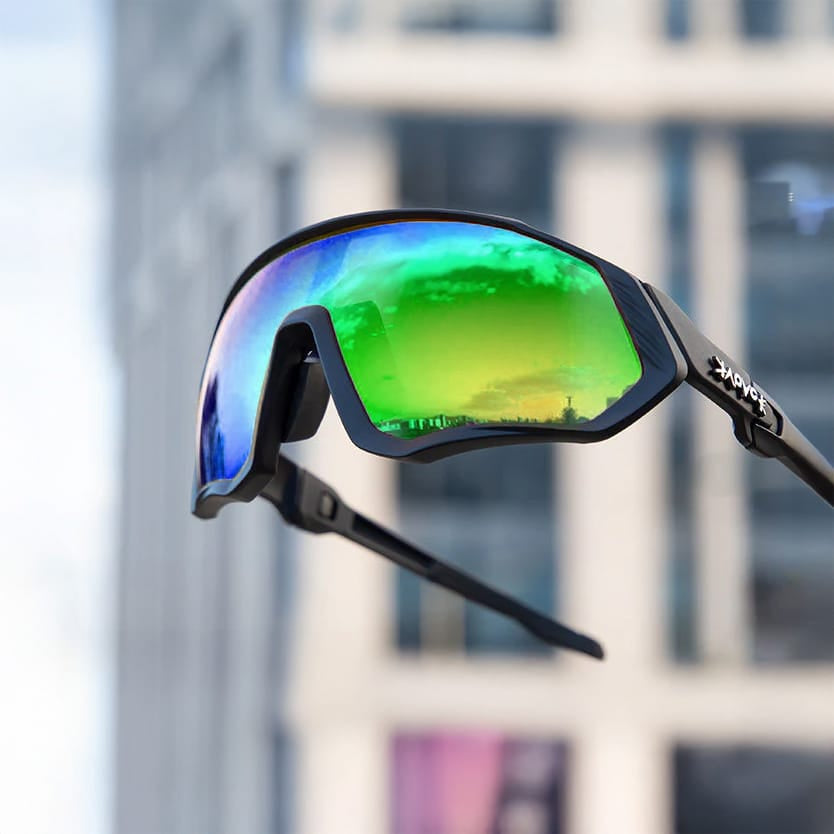 Grüne Sport-Sonnenbrille mit schwarzem Gestell mit Stadt im Hintergrund