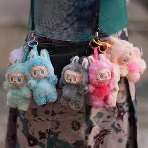 Sechs kleine Plüschtiere in verschiedenen Farben an einer Handtasche angebracht