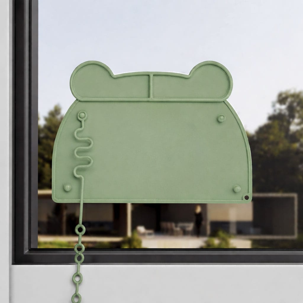 Grüne Silikonmatte in Bärenkopf-Form an einem Fenster befestigt