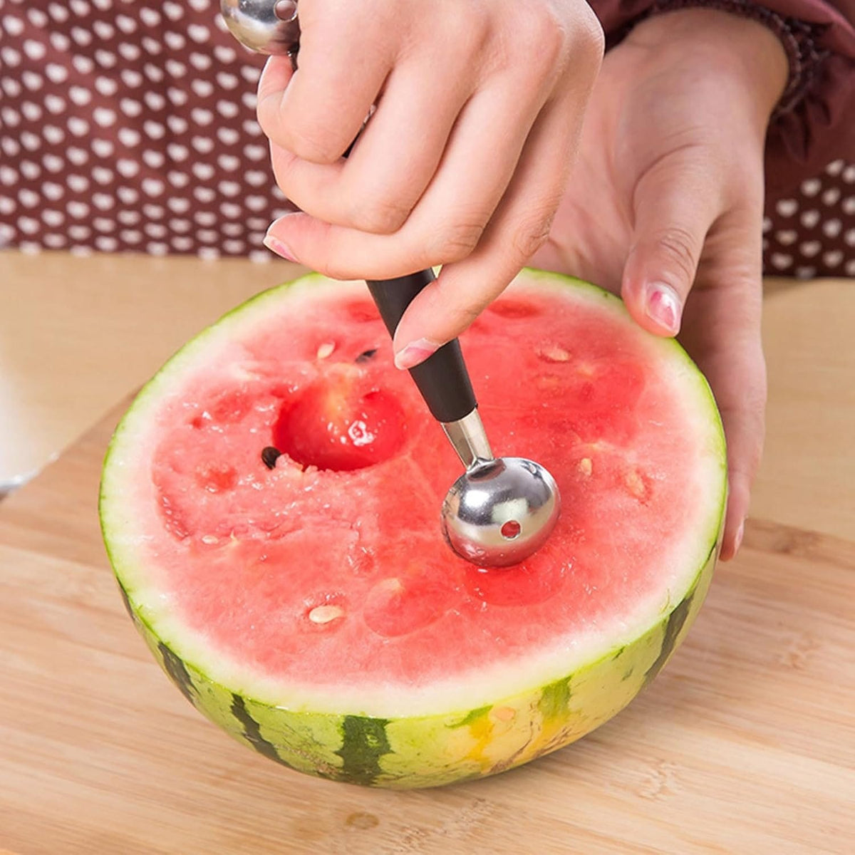 Silberner Kugelausstecher mit schwarzem Griff in einem Anwendungsbeispiel mit Wassermelone