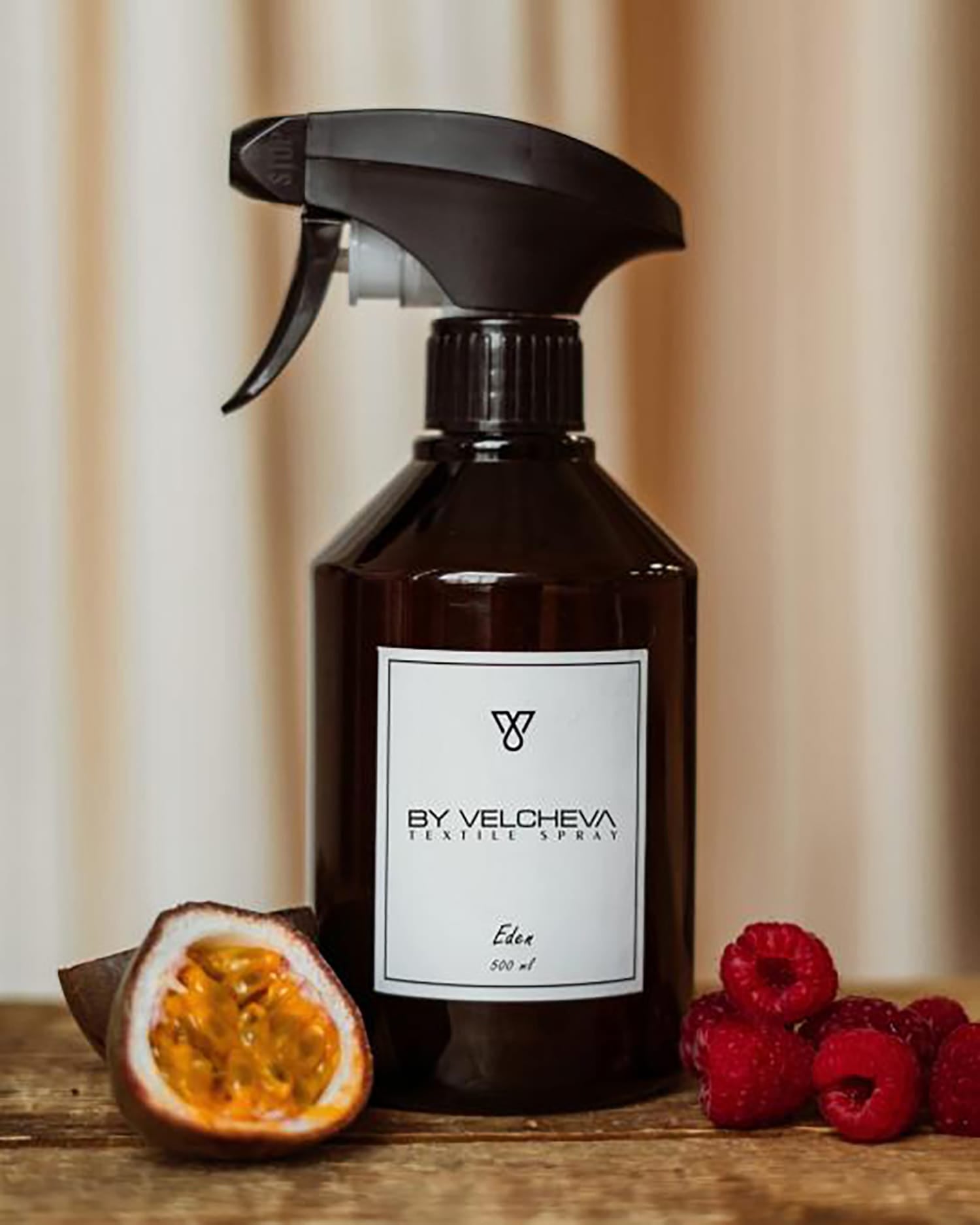 Braune Sprühflasche mit weissem Etikett neben Passionsfrucht und Himbeeren